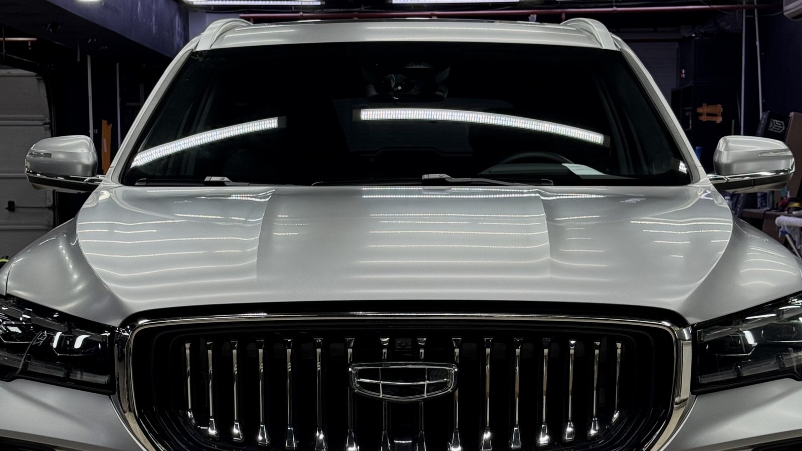 Geely Monjaro целиком в матовой полиуретановой плёнке: вид спереди в боксе АвтоЮвелир